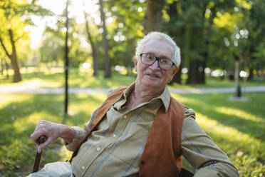 Smiling senior man sitting in park - HAPF03390