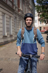 Lächelnder Mann mit Helm und Fahrrad an einem sonnigen Tag - KNSF09931