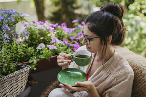 Woman enjoying her free time and a cup of coffee on the balcony - HAPF03409