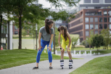 Mother teaches her daughter to roller skate in the city - HAPF03412