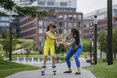 Mother teaches her daughter to roller skate in the city - HAPF03413