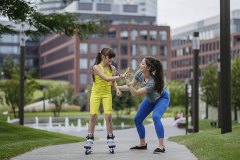 Mother teaches her daughter to roller skate in the city - HAPF03413