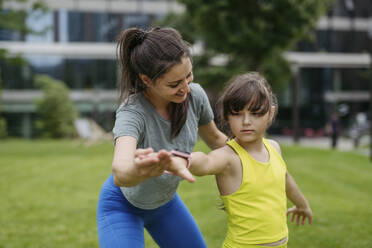 Mother and daughter spending together time outdoors practicing yoga - HAPF03419