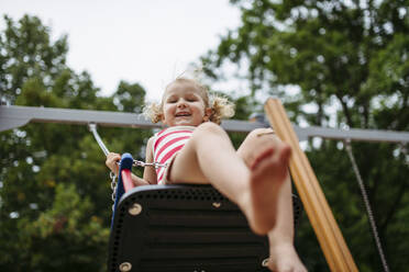 Little toddler girl and mother have fun at playground swinging on a swing - HAPF03440