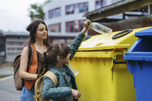 Mother and schoolgirl daughter separate waste into recycling bins in the city - HAPF03452