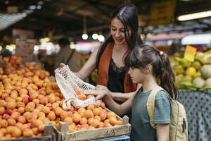 Mother and daughter shopping for fresh fruits and vegetables at the city market - HAPF03454