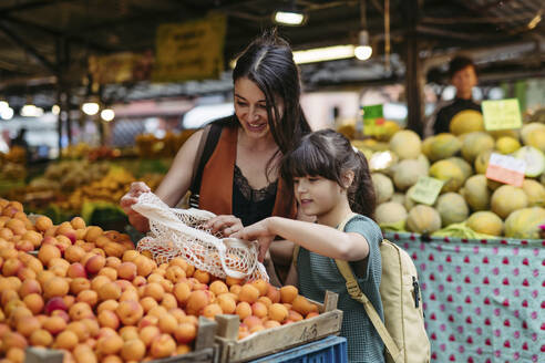 Mother and daughter shopping for fresh fruits and vegetables at the city market - HAPF03456