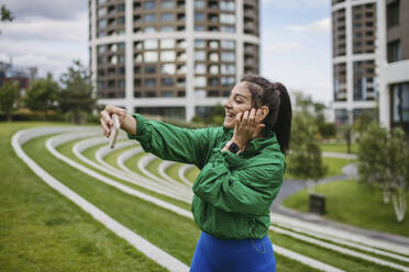 Woman training in city park having vodeo call over smartphone - HAPF03462