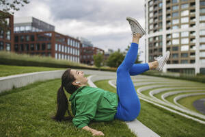 Laughing woman exercising in the city park listening music - HAPF03472