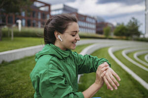 Beautiful woman exercising in a city park checking her performance on smart watch - HAPF03474