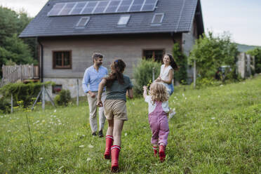 Happy girls running in garden of sustainable family home - HAPF03487