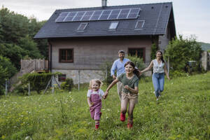 Happy girls running in garden of sustainable family home - HAPF03488