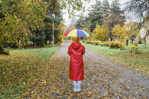 Frau in rotem Regenmantel und mit Regenschirm im Park - VBUF00486