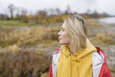 Thoughtful blond woman wearing hooded shirt in autumn park - VBUF00495