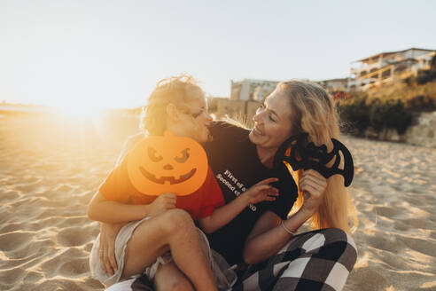 Glückliche Mutter und Tochter genießen zusammen mit Halloween Spielzeug am Strand - SIF01071