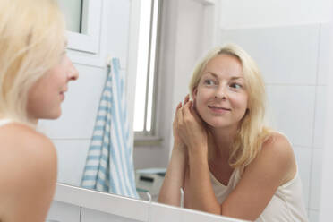 Smiling woman getting dressed looking in mirror at home - VGF00425