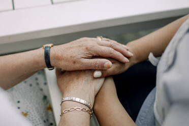 Midsection of senior man and female nurse holding hands at retirement home - MASF40203