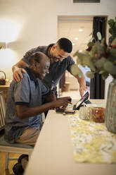 Happy male nurse assisting senior man in using digital tablet and smart phone at nursing home - MASF40217