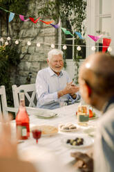 Happy senior men sitting at dining table in back yard - MASF40249