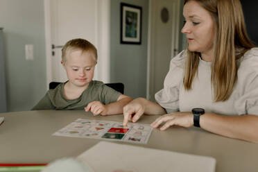 Mother teaching son with down syndrome at home - MASF40310