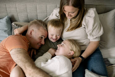 High angle view of happy family enjoying on bed at home - MASF40333