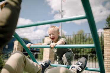 Boy with down syndrome and father at jungle gym in park - MASF40349