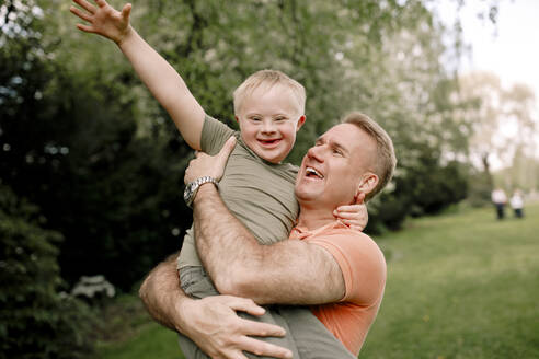 Glücklicher Mann mit Sohn mit Down-Syndrom im Park - MASF40355