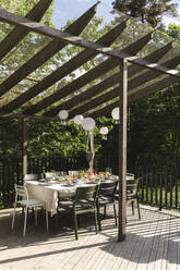 Lanterns hanging over dining table at patio on sunny day - MASF40369