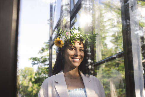 Porträt einer lächelnden Frau, die während des schwedischen Mittsommerfestes ein Blumen-Diadem trägt - MASF40383