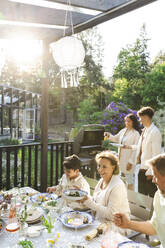 Family enjoying summer dinner party at back yard - MASF40389