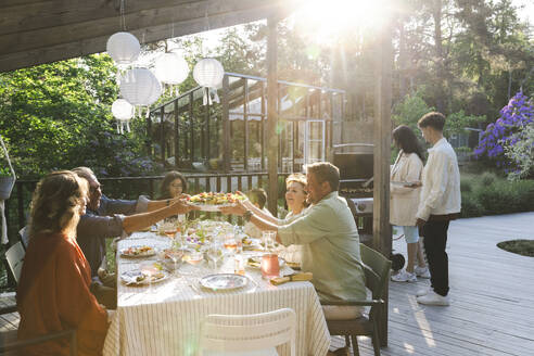 Family and friends enjoying summer dinner at patio in back yard - MASF40390