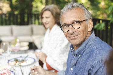 Portrait of smiling retired senior man sitting at dining table - MASF40392