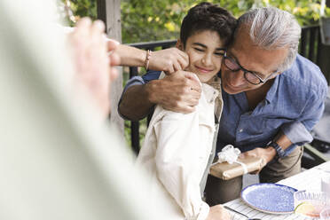 Senior man hugging grandson during midsummer dinner party - MASF40394