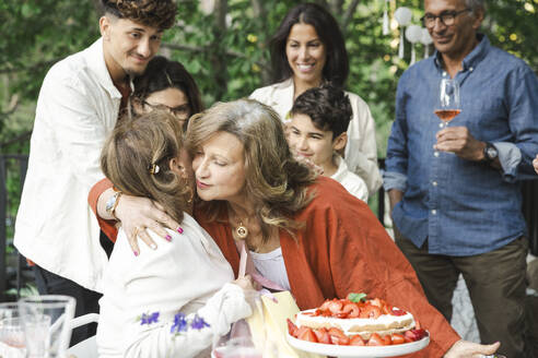 Women embracing each other near family during dinner party - MASF40400
