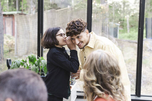 Boy whispering to young man at patio during party - MASF40438