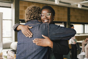 Smiling businesswoman embracing male colleague at office - MASF40472