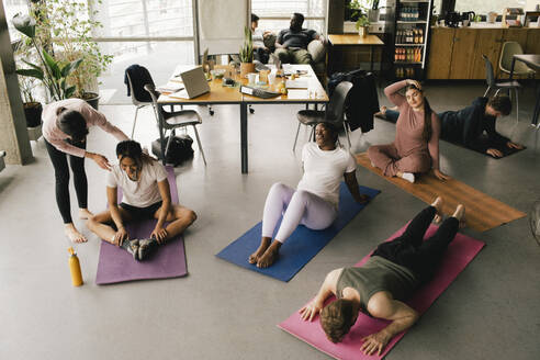 High angle view of multiracial colleagues exercising together at workplace - MASF40504