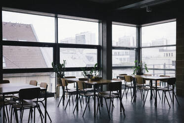 Empty desks and chairs by window at workplace - MASF40524