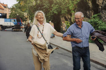 Cheerful senior couple strolling on street in city - MASF40528