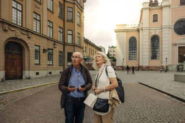 Confused senior couple standing on street in city - MASF40532