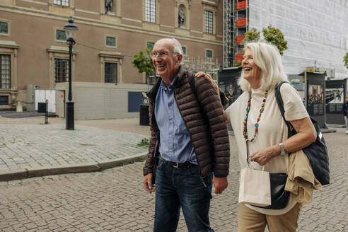 Happy retired senior couple walking on street in city - MASF40534