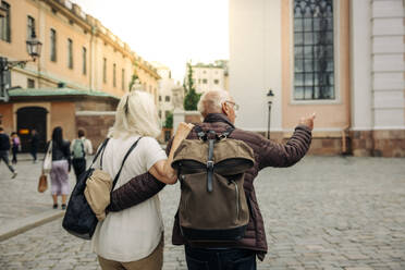 Rear view of retired senior couple walking on street in city - MASF40535