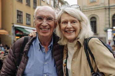 Portrait of happy senior couple with arm around in city - MASF40552