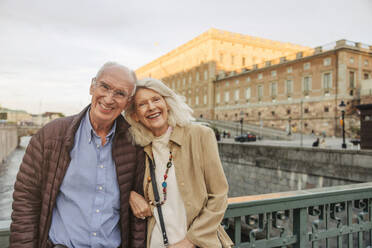 Porträt eines glücklichen älteren Mannes und einer Frau, die sich auf ein Geländer in der Stadt stützen - MASF40557
