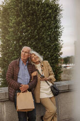 Thoughtful senior couple leaning on railing while looking away - MASF40564