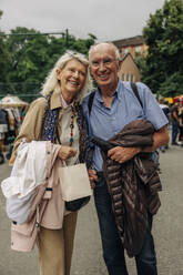 Happy retired senior tourist couple standing on street in city - MASF40576