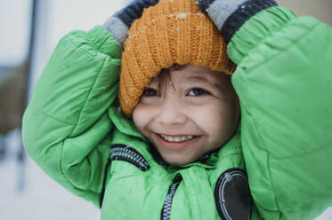 Glücklicher Junge mit gelber Strickmütze im Winter - ANAF02394