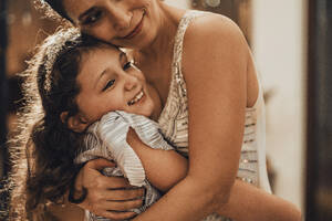Lächelnde Mutter und Tochter, die sich zu Hause umarmen - MFF09442