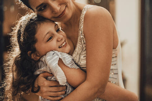Smiling mother and daughter hugging at home - MFF09442