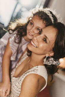 Smiling daughter wearing hairband with mother at home - MFF09446